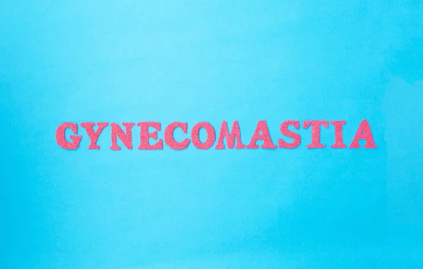 Palabra ginecomastia en letras rojas sobre fondo azul. El concepto de cirugía plástica para ajustar los senos masculinos —  Fotos de Stock