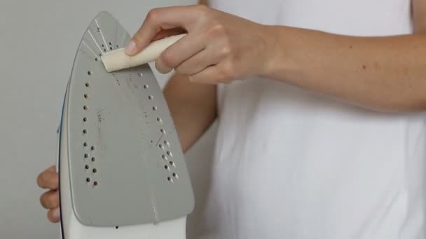 The girl cleans the iron from carbon deposits with a special cleaning pencil. — Stock Video