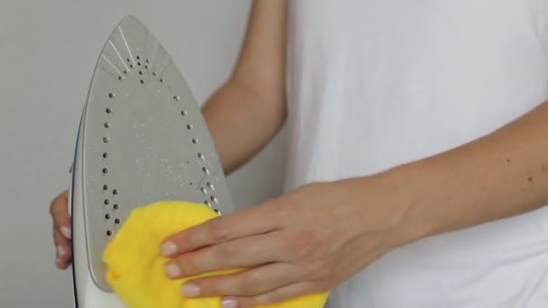 La ragazza pulisce la superficie dei depositi di carbonio sul ferro con uno straccio giallo — Video Stock