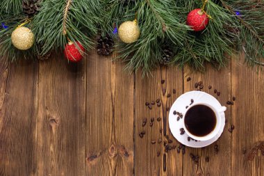 Kahverengi ahşap arka planda bir fincan kahve ve çam fıstığı. Tüylü, yeşil bir Noel ağacının dalında yeni yıl topları. Yeni yıl ve Noel tatili konsepti, kopyalama alanı