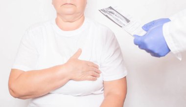 Doktor kalp sorunu olan yaşlı bir kadının muayenesinin sonuçlarını elinde tutuyor. Kardiyovasküler hastalık konsepti, iskemi ve anjini pektorisi, tıbbi