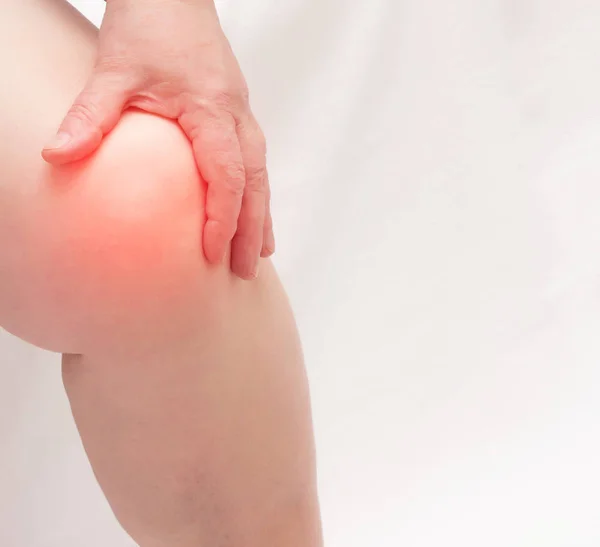 Een oudere vrouw houdt het kniegewricht vast aan haar been. Pijn en ontsteking in de knie, ziekten vervormende artrose en meniscus verwondingen, kopieer ruimte — Stockfoto