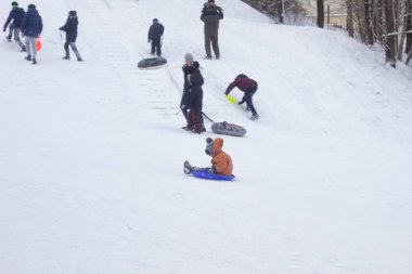 Birçok insan kışın karda bir kızağa biner, çocuklar ve yetişkinler. Bobruisk, Belarus - 03.01.19
