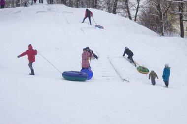 Birçok insan kışın karda bir kızağa biner, çocuklar ve yetişkinler. Bobruisk, Belarus - 03.01.19