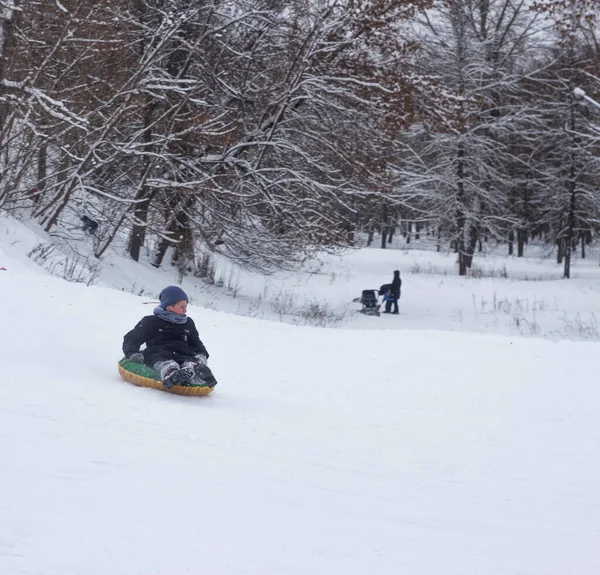 Πολλοί άνθρωποι παιδιά και ενήλικες οδηγούν ένα έλκηθρο το χειμώνα στο χιόνι. Bobruisk, Λευκορωσία - 03.01.19 — Φωτογραφία Αρχείου