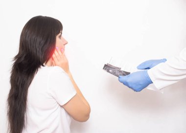 Kız doktor randevusundaki bir hasta. Tükürük bezinin muayenesinin sonuçları elinde. Tükürük bezleri ve lenf bezlerinin iltihaplanması, kanser...