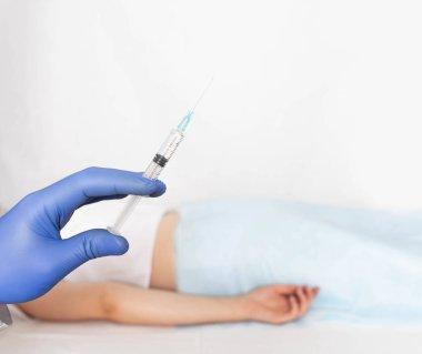 Doktor, varisli ve basurlu bir hastanın arka planına karşı eldivenin içinde bir şırınga tutuyor. Skleroterapi tedavi kavramı, kopyalama alanı