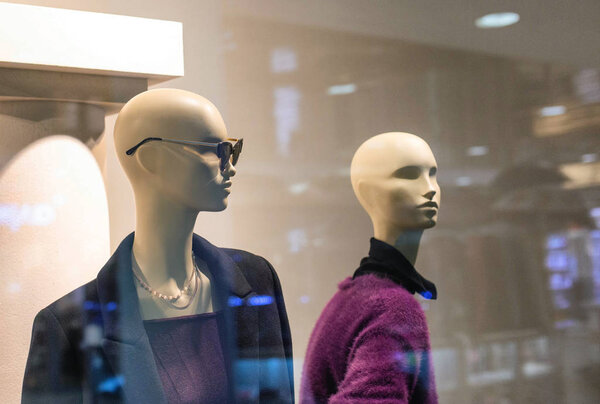Two fashionable and stylish mannequins in modern glasses and warm business clothes. The concept of selling quality and stylish clothes, background