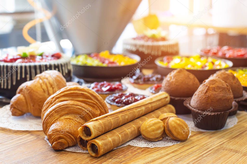 Production for the production of desserts. Croissants and cake in tartlets with cakes, nuts with condensed milk lie on a wooden table, torte
