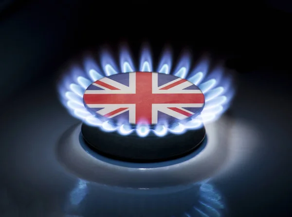 Burning gas burner of a home stove in the middle of which is the flag of the country of United Kingdom. Gas import and export delivery concept, price per cubic meter, transit, background