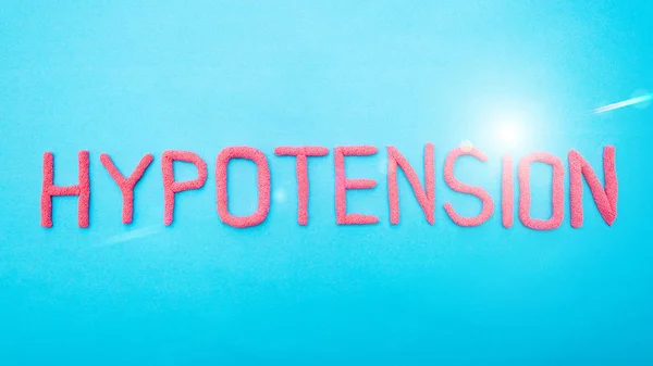 Hipotensión de la palabra de letras rojas sobre un fondo azul. Hipertensión arterial concepto de enfermedad, médico, inscripción —  Fotos de Stock
