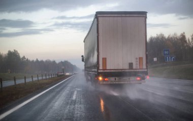 Karavanı olan bir kamyon kaygan yollarda farklı bir sırada otoyolda yeniden inşa ediliyor. Kötü havada yollara dikkat ve güvenlik kavramı, yağmur...