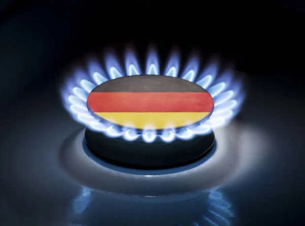 Burning gas burner of a home stove in the middle of which is the flag of the country of Germany. Gas import and export delivery concept, price per cubic meter, transit, background