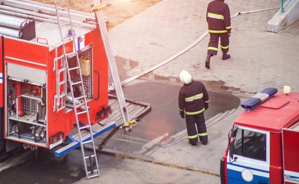 Bombeiros resgatam extinguir um incêndio em um prédio residencial, esticar mangueiras de incêndio para abastecimento de água — Fotografia de Stock