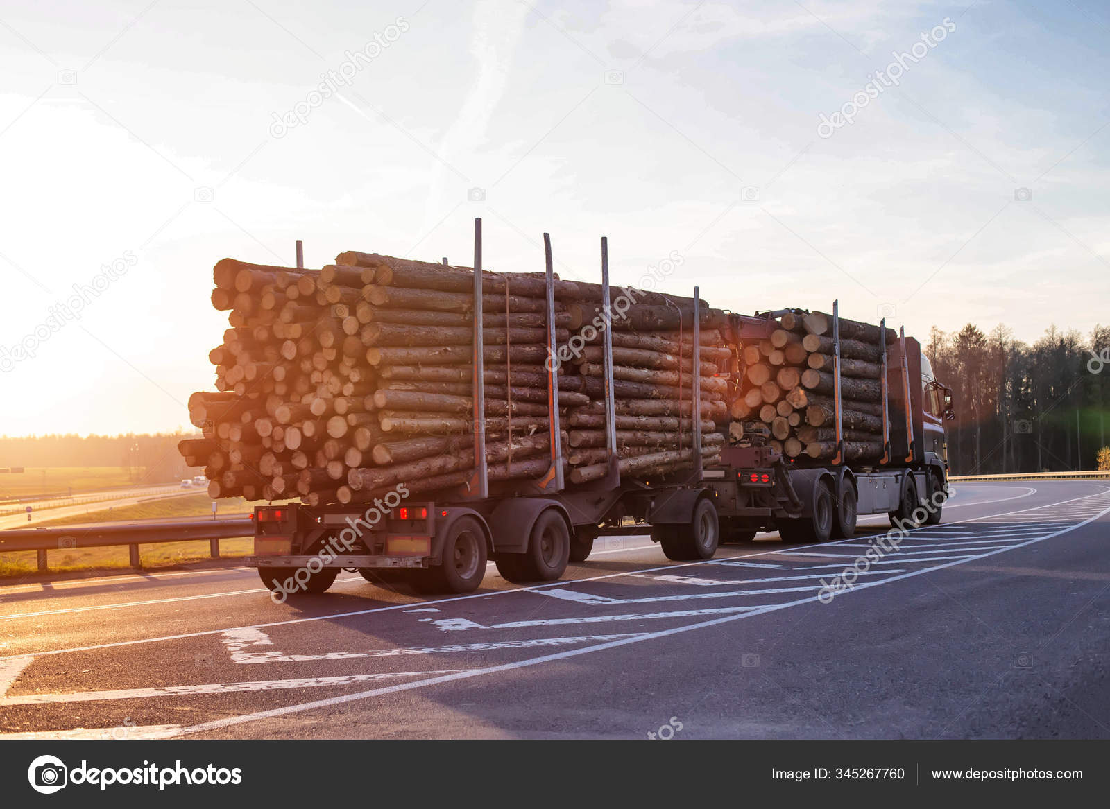 En tømmerbil bærer tømmer langs veien mot bakteppet av en solnedgang.  Eksport og import av tre, industrielt konsept – stockfoto ©  Genrix20061.mail.ru #345267760, image size:1600x1167