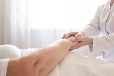 Doktor yaşlı bir kadının elini bir pencerenin arka planında tutuyor. Hastanede, yaşlılarda, fotokopi alanlarında hijyenik hasta bakımı kavramı