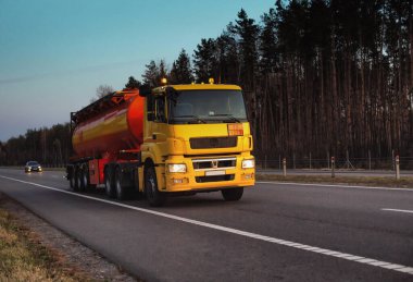 Bir kamyon, orman ve mavi gökyüzüne karşı bir otoyolda yanıcı yakıt deposu taşıyor. Tehlikeli malların yolda taşınması kavramı