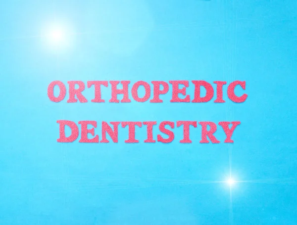 The word orthopedic dentistry in red letters on a blue background. The concept of the section of dentistry dealing with prosthetics in the oral cavity