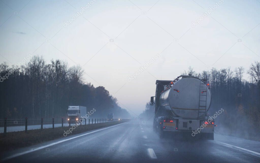 A truck wagon rides on a motorway in fog and rain. The concept of poor visibility on the road
