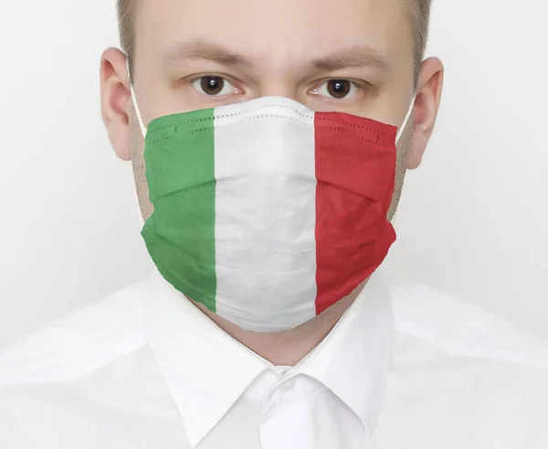 얼굴에 보호용 마스크를 쓰고 있는 이탈리아의 깃발을 들고 있는 남자. 나라 안에서 코로나 바이러스와 바이러스 감염의 개념, 초상화 — 스톡 사진