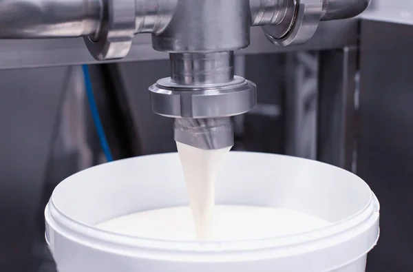 Making and spilling yogurt from milk into buckets. Making milk products, close-up. Food industry