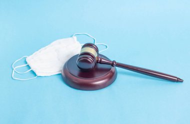 Mavi arka planda adli tokmak ve koruyucu tıbbi maske. Koronavirüs salgını sırasında yasadışı koruma maskesi satışı ve aşırı satış yapma kavramı, tehlike