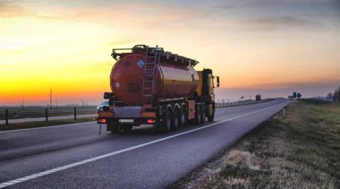 Bir kamyon, orman ve mavi gökyüzüne karşı bir otoyolda yanıcı yakıt deposu taşıyor. Tehlikeli malların yolda taşınması, ruhsat...