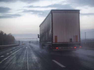 Yağmurun, sislerin, arka planda olduğu yerlerde görüş mesafesi zayıf bir otoyolda giden bir kamyon. Kötü Yol Güvenliği Konsepti, kopyalama alanı