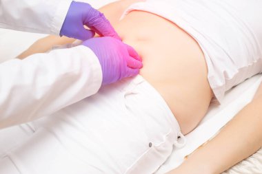 Doktor, mesanesinde iltihap ve ağrısı olan bir kızda karın boşluğunu inceliyor. Kızlardaki hastalık kavramı: Sistit, böbrek taşı, dismenorafi.