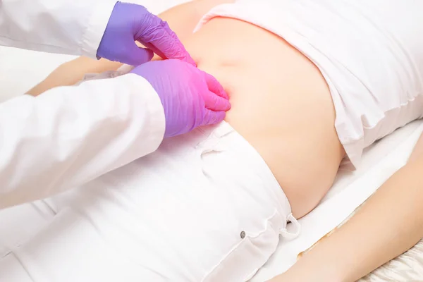 Doktor, mesanesinde iltihap ve ağrısı olan bir kızda karın boşluğunu inceliyor. Kızlardaki hastalık kavramı: Sistit, böbrek taşı, dismenorafi.