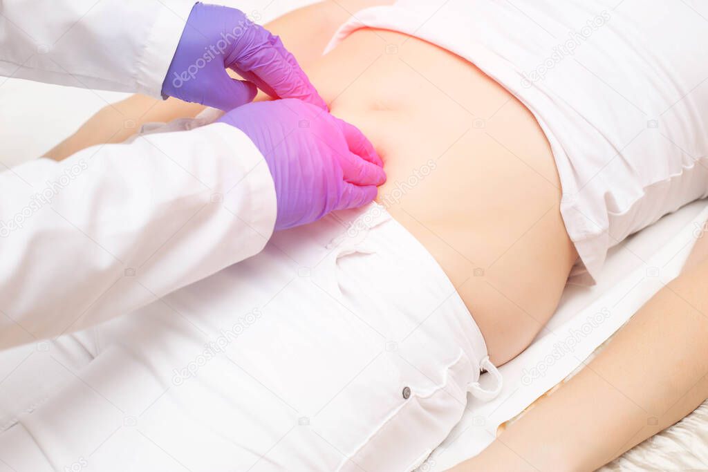 The doctor probes the lower abdomen in a girl who has pain and inflammation of the bladder. The concept of diseases in girls cystitis, kidney stones, dysmenorrhea