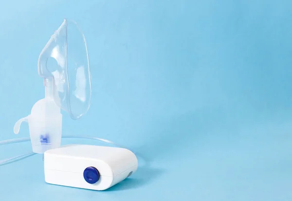 Um dispositivo de tratamento de nebulização para o tratamento da inflamação das vias aéreas, tosse e pneumonia. Prevenção da asma brônquica, fundo azul, espaço de cópia, cuidados de saúde — Fotografia de Stock