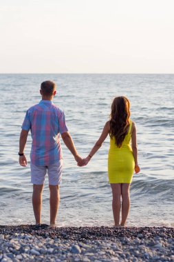 Kumsalda yürüyen ve el ele tutuşan bir çift.