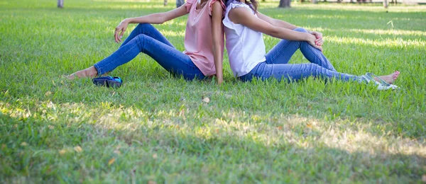 两个十几岁的女孩朋友坐在草地上 — 图库照片
