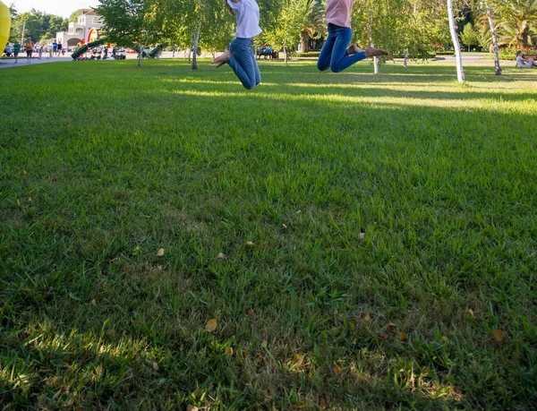 两个十几岁的女孩朋友跳上草地 — 图库照片