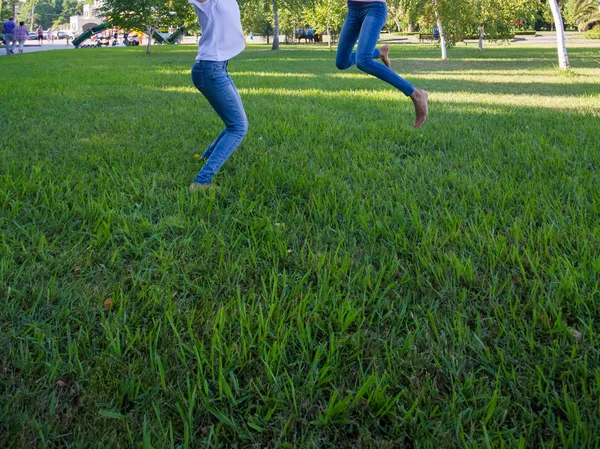 两个十几岁的女孩朋友跳上草地 — 图库照片
