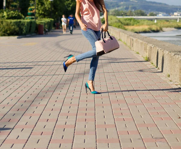 ピンクのブラウスと青いジーンズの女の子と堤防の上を歩くハンドバッグ — ストック写真