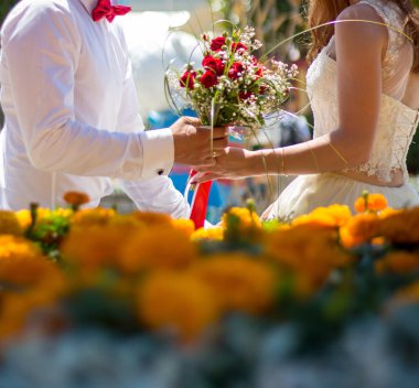 Gelin ve damat düğün buketi taşıyor.