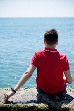 Adam deniz kıyısında oturuyor.