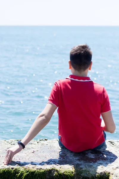 Adam deniz kıyısında oturuyor.