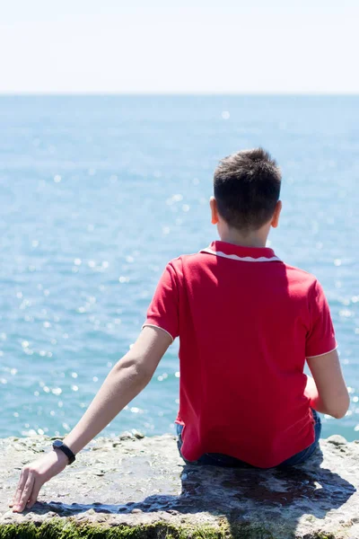 Adam deniz kıyısında oturuyor.