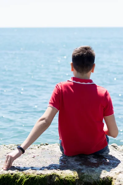 Adam deniz kıyısında oturuyor.