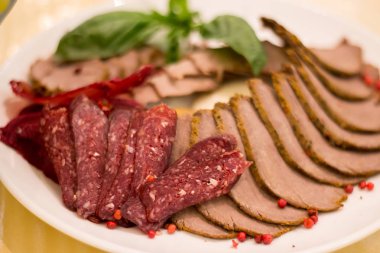 Bir tabakta dilimlenmiş jambon ve salam