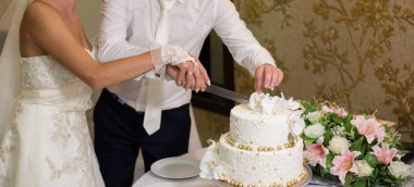 Gelin ve damat bir düğünde pasta kesiyorlar.