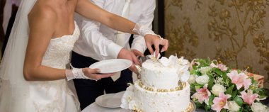 Gelin ve damat bir düğünde pasta kesiyorlar.