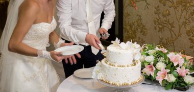 Gelin ve damat bir düğünde pasta kesiyorlar.