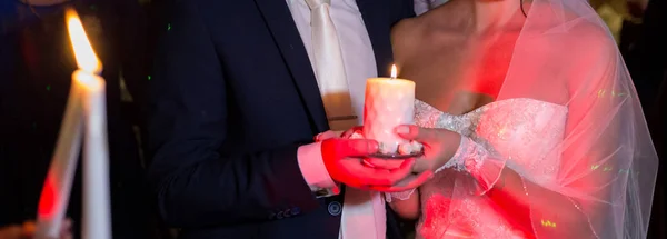 Candle in the hands of the bride and groom at the wedding