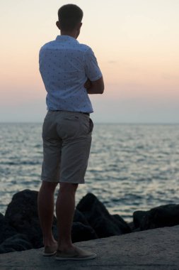 Deniz kıyısı üzerinde duran bir adam