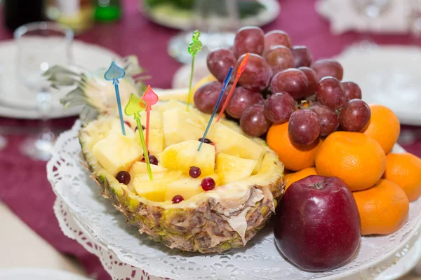 Dish with fruit. Pineapple, apple, mandarin, grapes