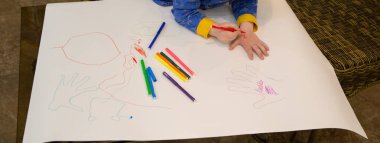 Çocuk keçeli kalemlerle resim yapıyor.